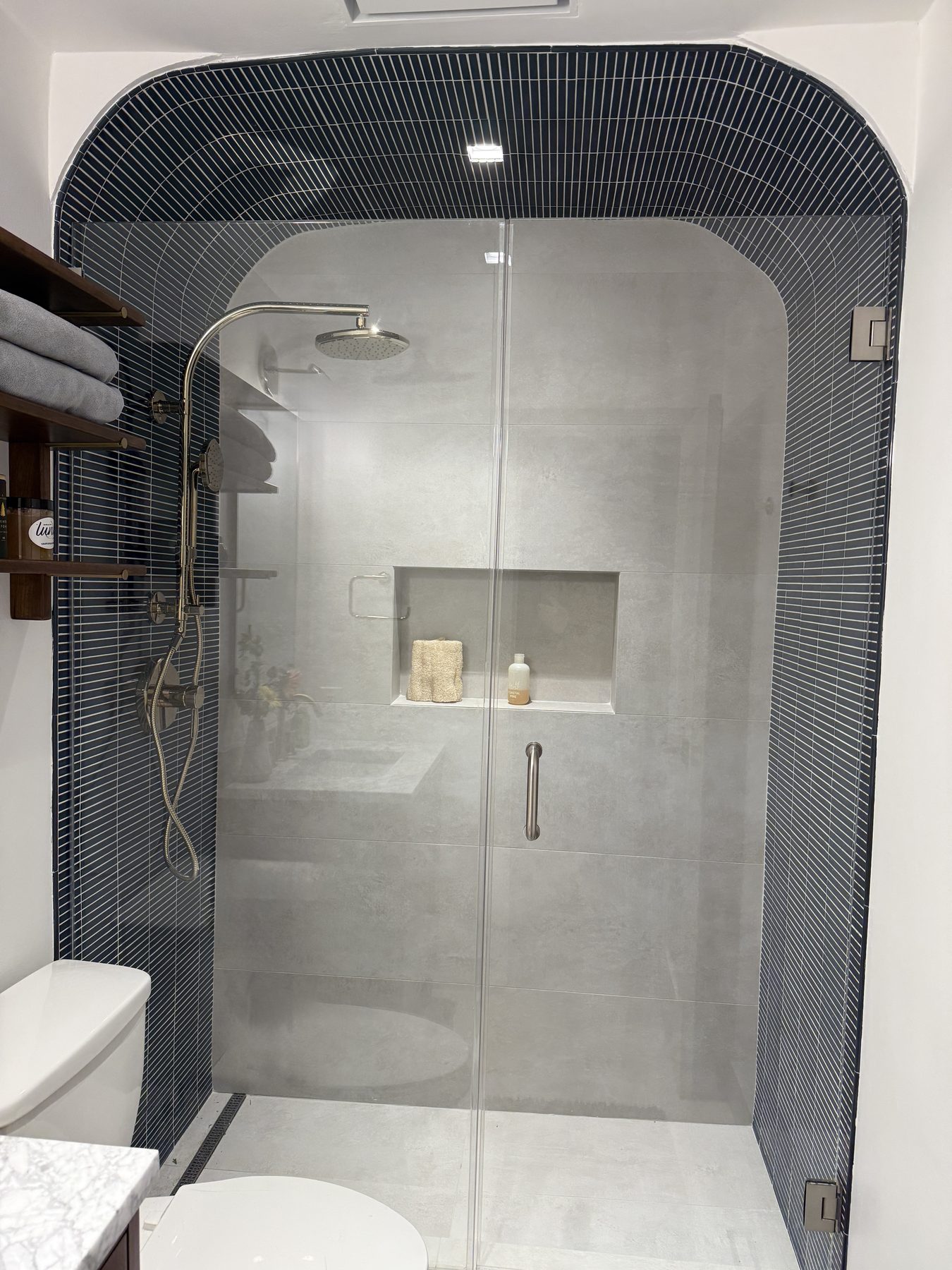 Brushed brass shower fixture against deep green zellige tile